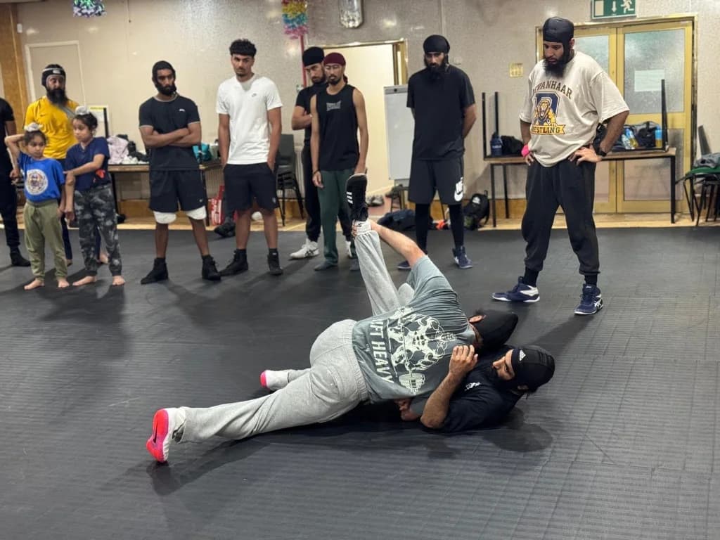 Wrestlers demonstrating groundwork on the academy mats