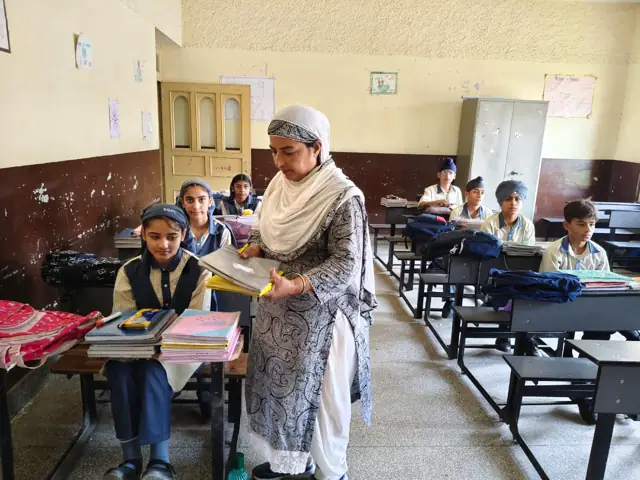 A teacher supporting a pupil at a classroom desk